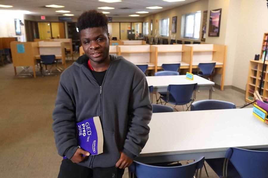 Student leaning on table with GED Studyguide