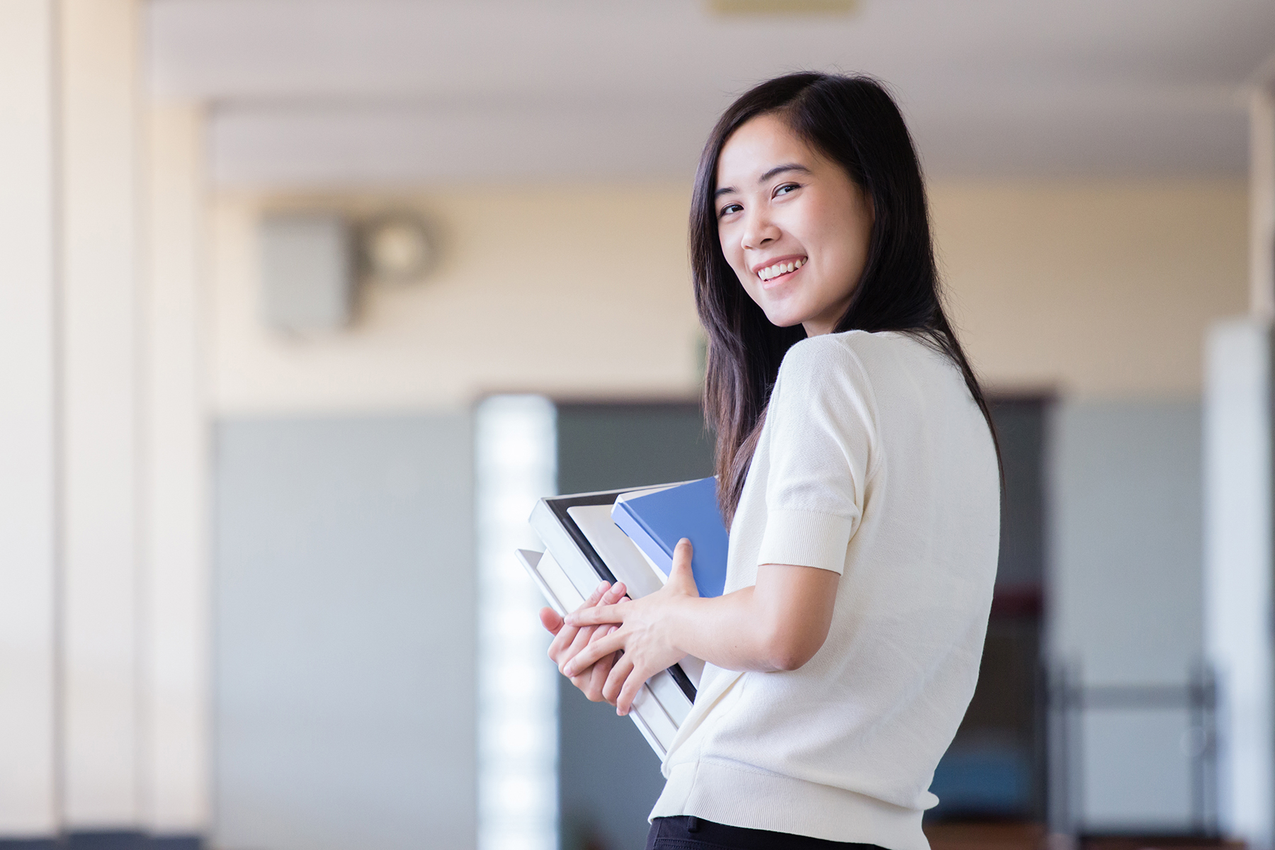 Young woman with stack of books