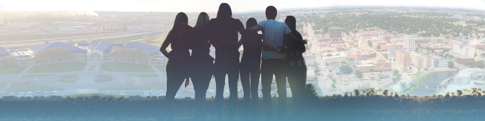 silhouettes of a group of people with Sioux Falls and Southeast Tech in background