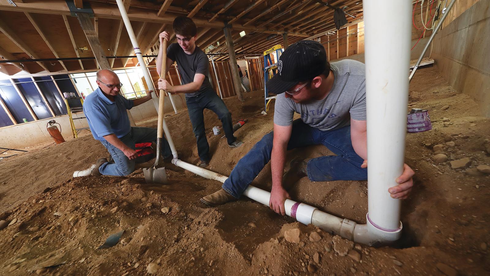 Plumbing students working with plumbing instructor to set up plumbing
