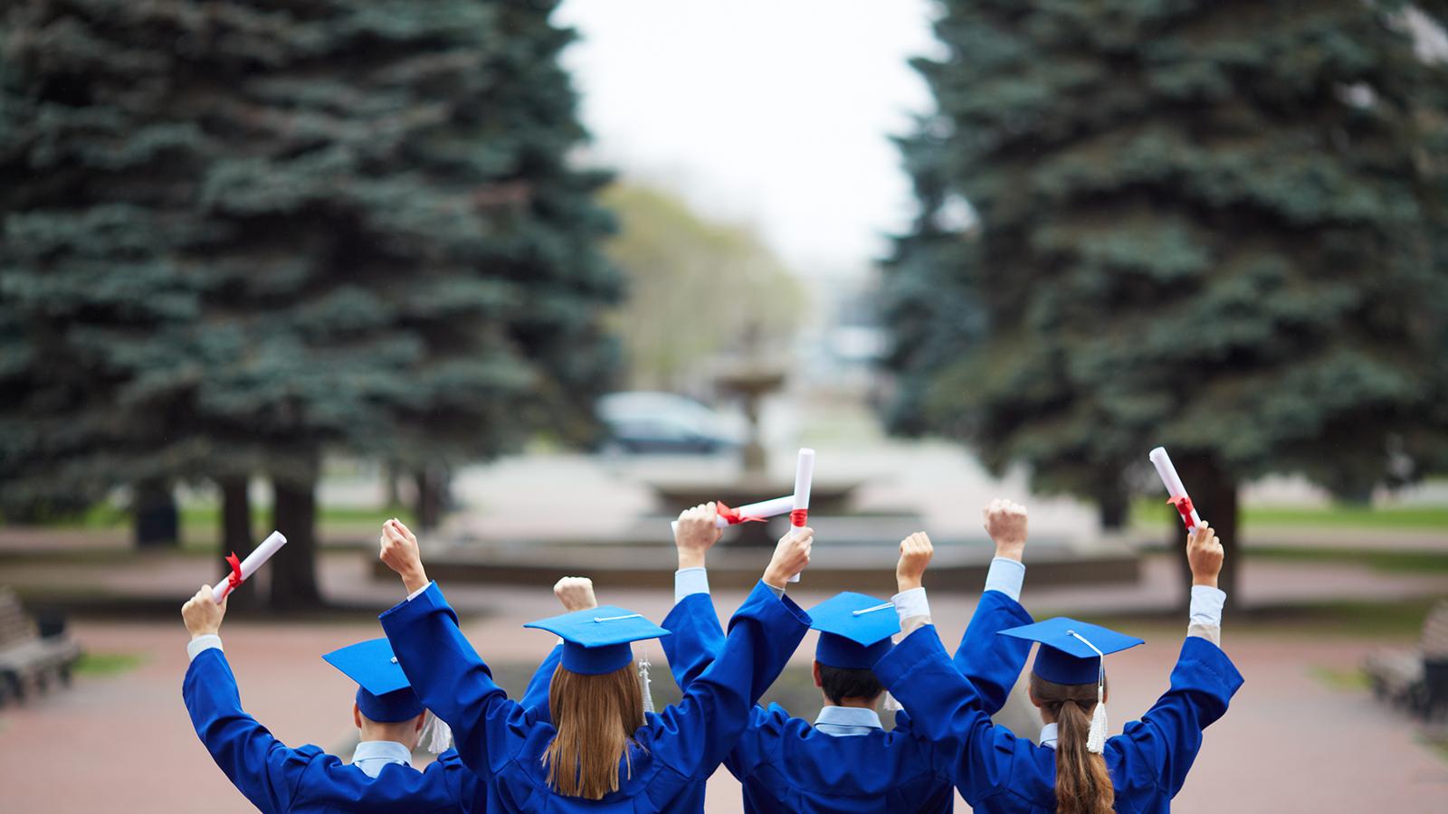Graduates in cap and gown holding diplomas