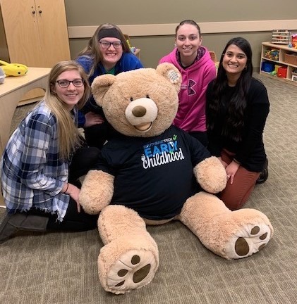 four female students with giant teddy bear