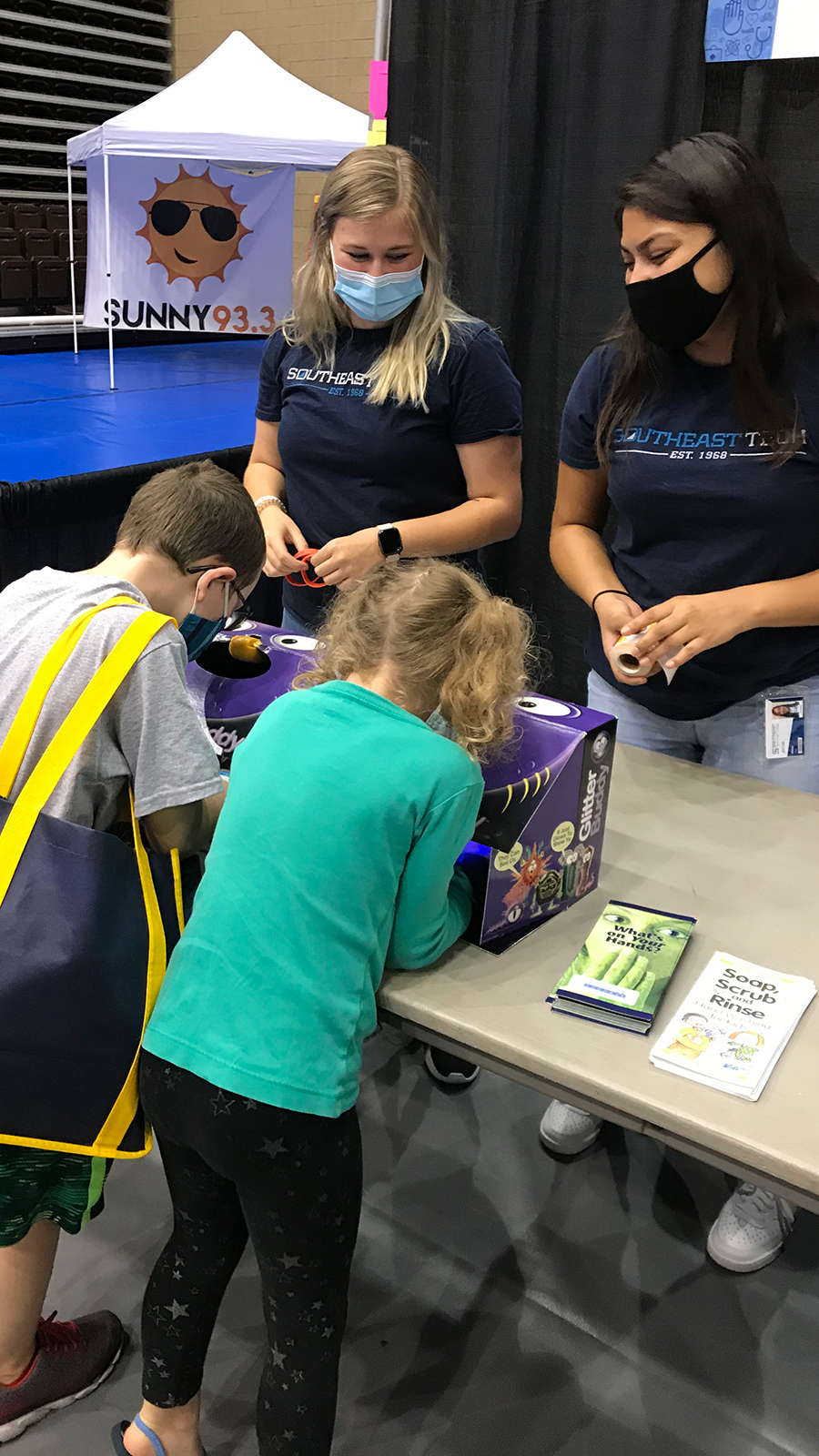 Student helps child learn about lungs at health fair.