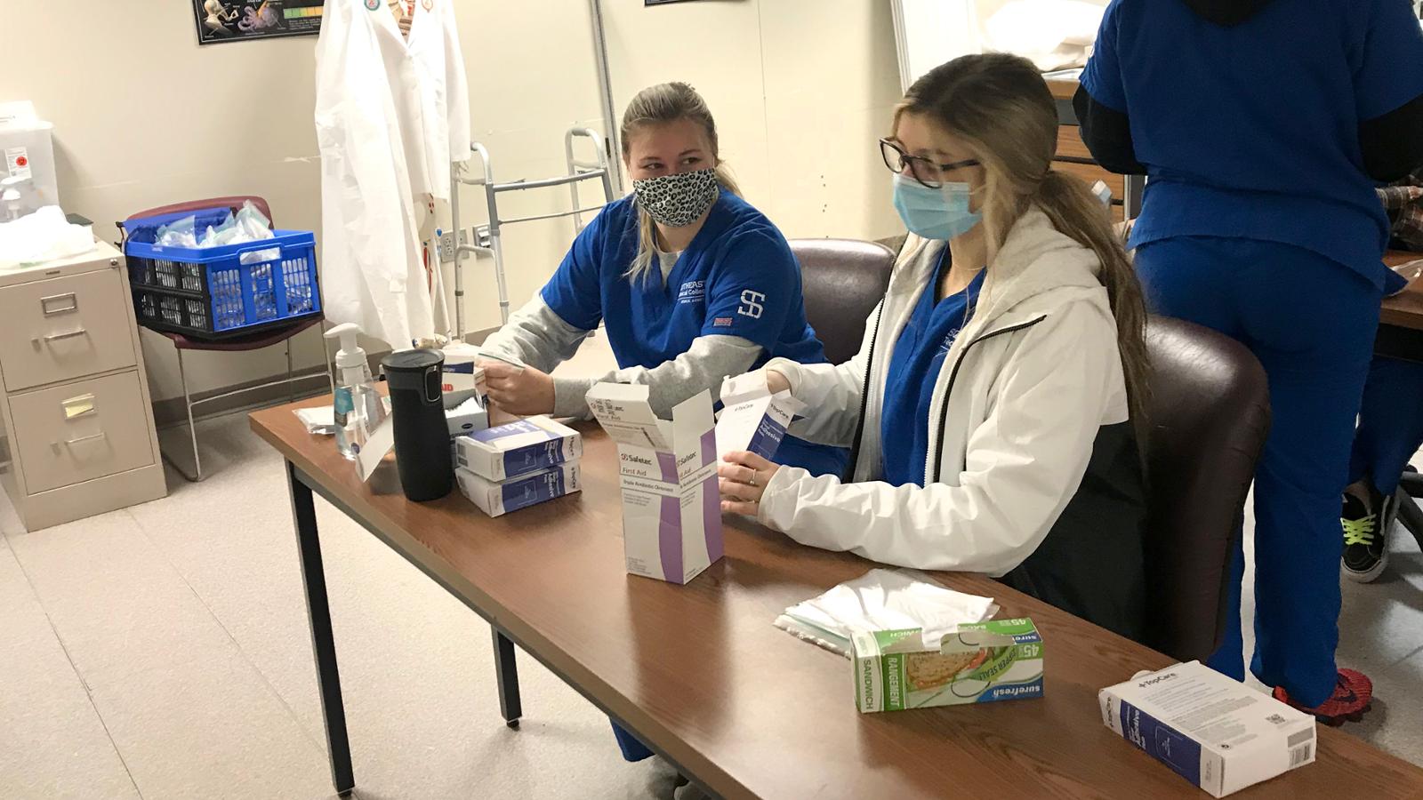 two students working on assembling care kits