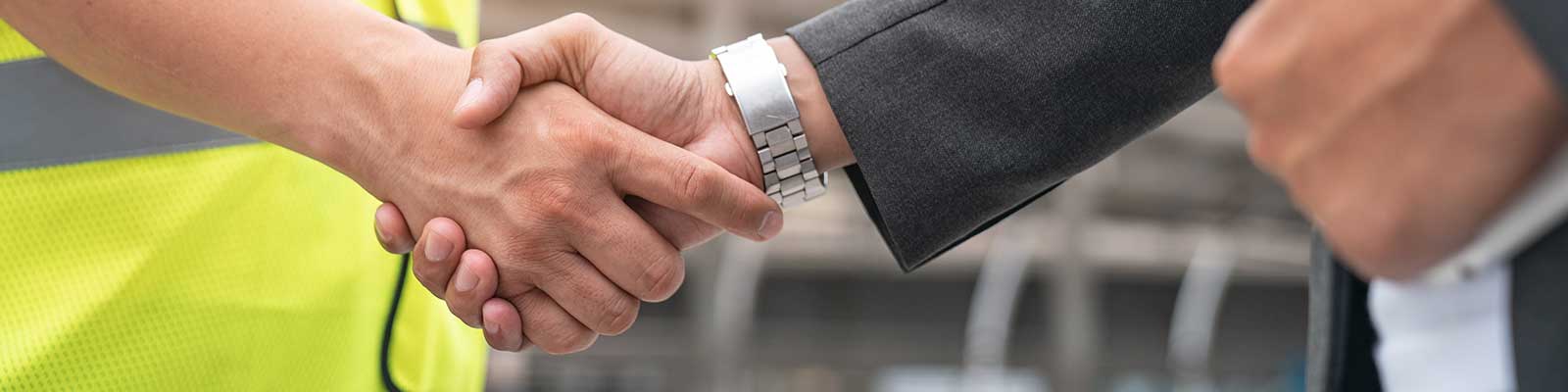 close up of handshake between man in suit and construction vest