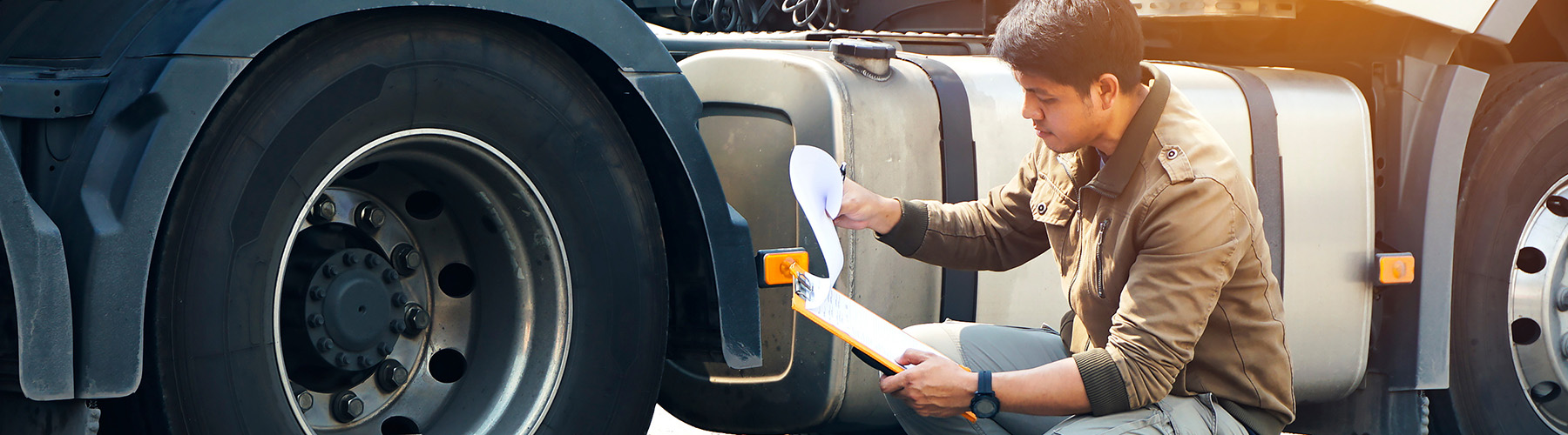 young driver kneeling by tire doing a vehicle inspection