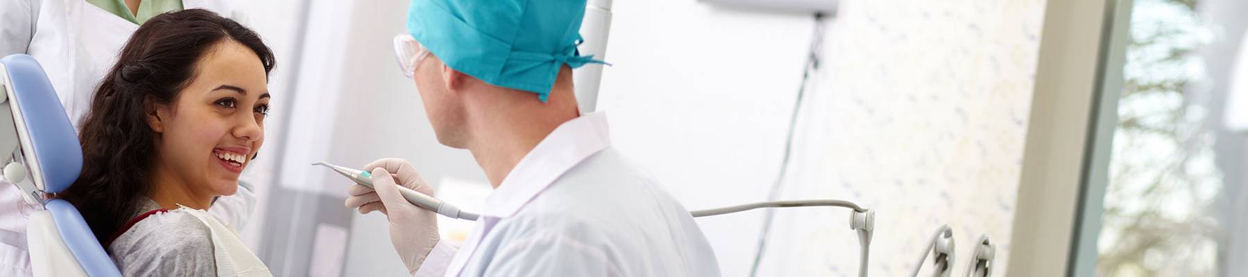 Woman in dental exam room smiling, dentist about to exam