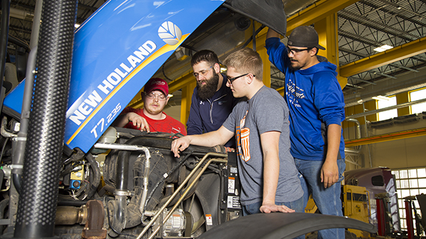 Students under hood of New Holland tractor