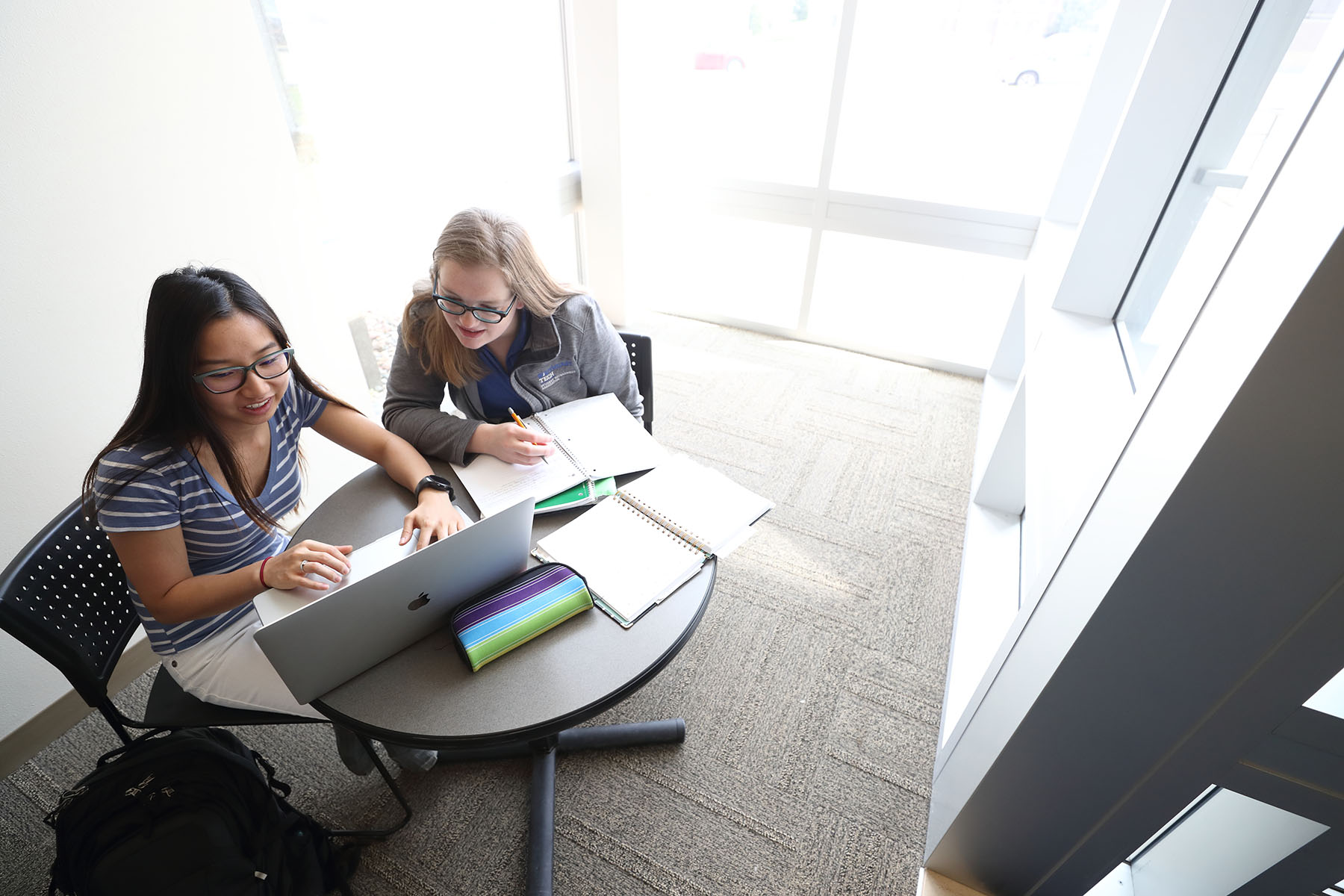 Students in sunny study area with large windows