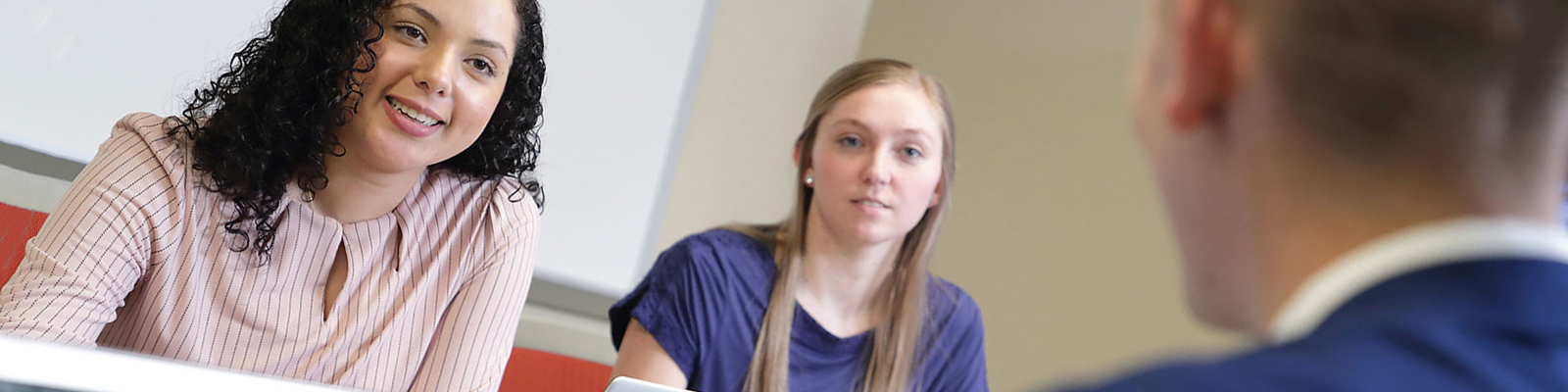 Student discussion in conference room, girl in background in focus