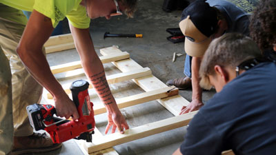 Students working on wood framing on ground