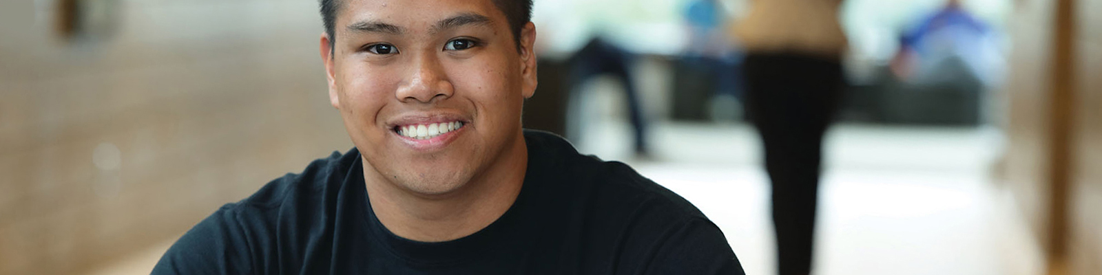 Smiling male student at a study table at Southeast Tech with an open binder in front of him.