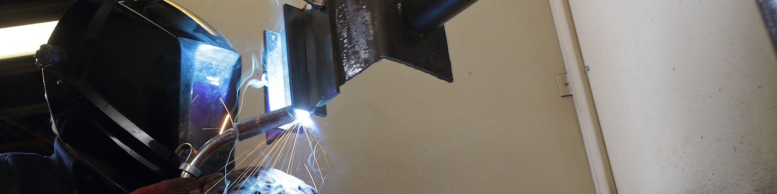 Birds eye view of a Southeast Tech student in welding gloves and mask using a torch on a weld.