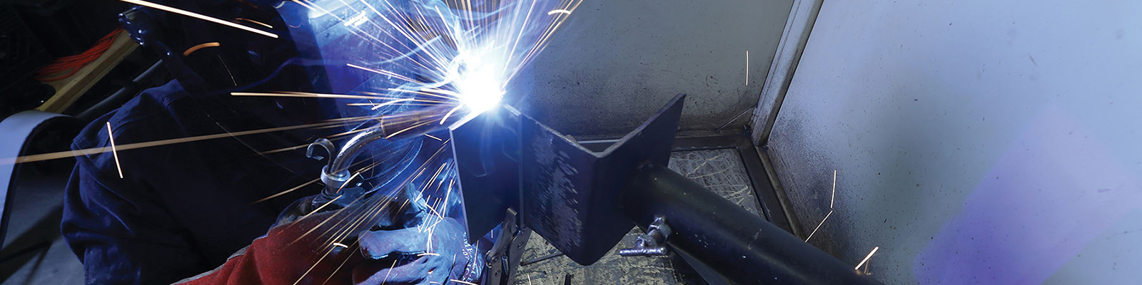 Side view of a Southeast Tech student in welding gloves and mask using a torch on a weld.