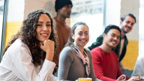 Diverse group of young adults in well lit room, smiling