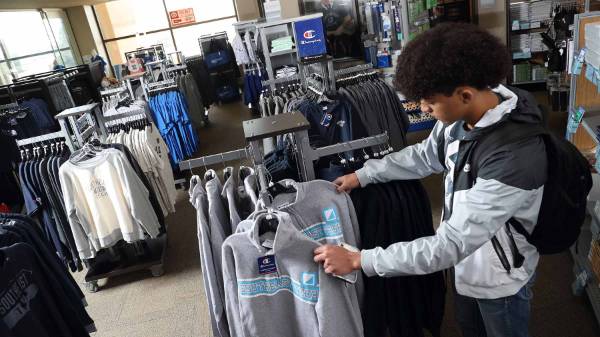 student looking at sweatshirts in a rack