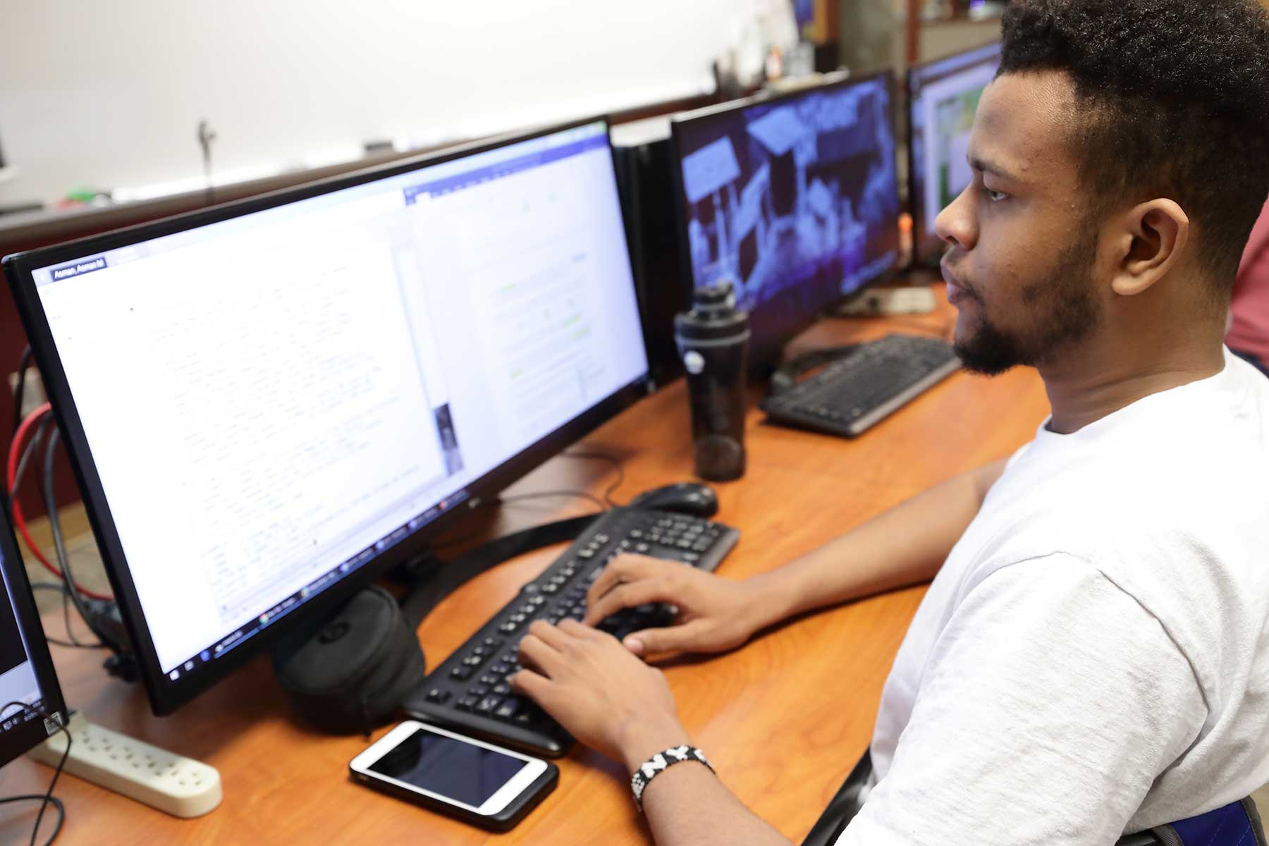 student in front of dual computer monitors